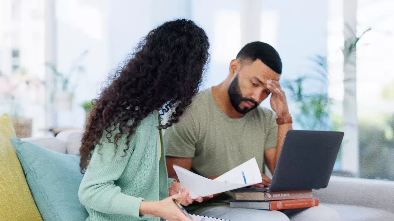 couple reviewing bills and a laptop, appearing worried
