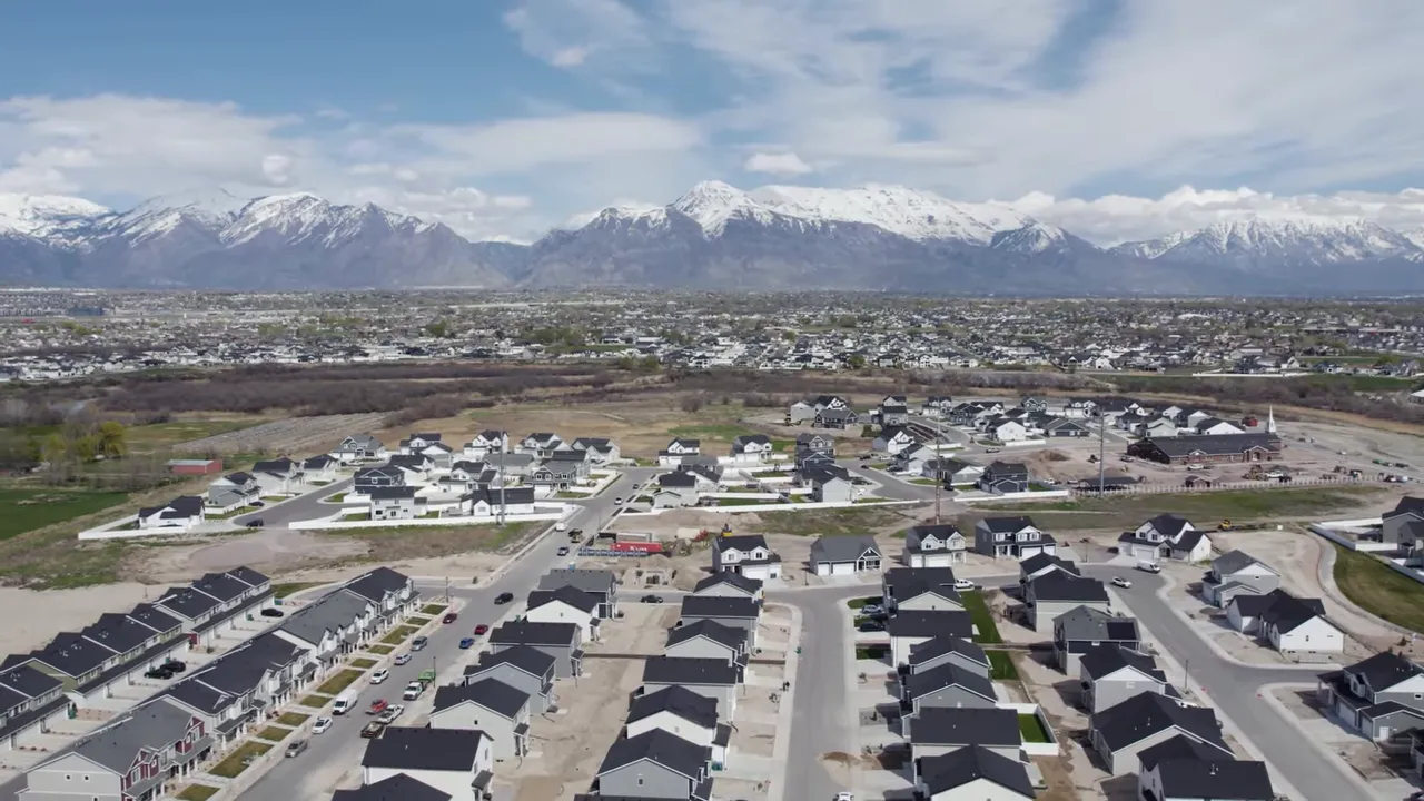 Wide aerial of Utah suburbs with snow-capped mountains in the distance illustrating expanding housing inventory.