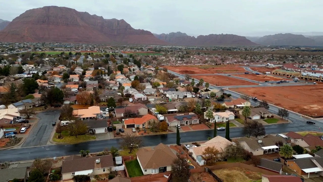 Drone view of St. George showing residential areas with red sandstone mountains in the distance